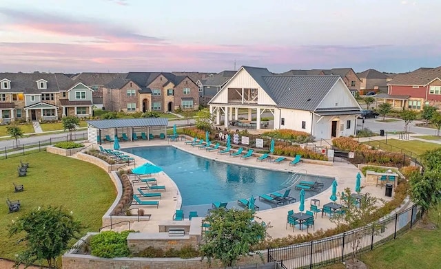 community pool with a patio area, a residential view, a yard, and fence