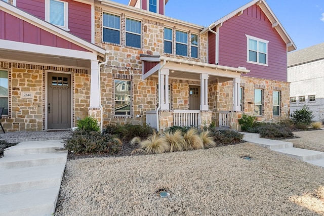 view of front of home with stone siding, covered porch, and board and batten siding