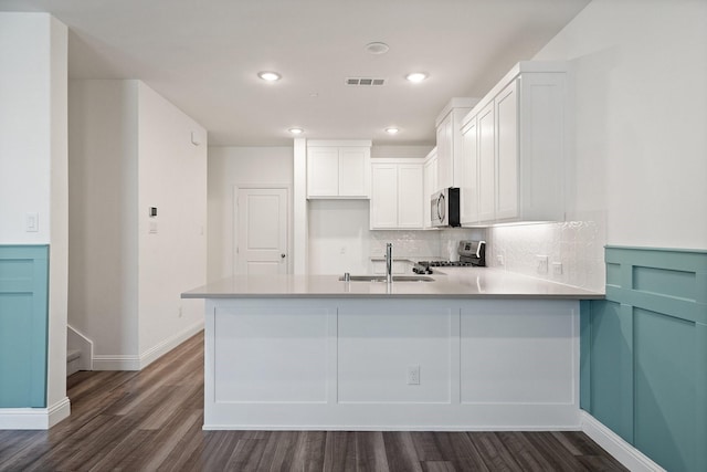 kitchen with visible vents, a peninsula, a sink, appliances with stainless steel finishes, and white cabinetry