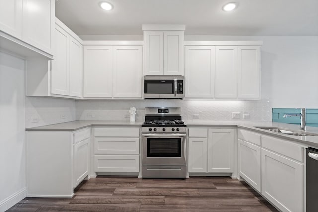 kitchen featuring backsplash, appliances with stainless steel finishes, dark wood-style floors, white cabinets, and a sink