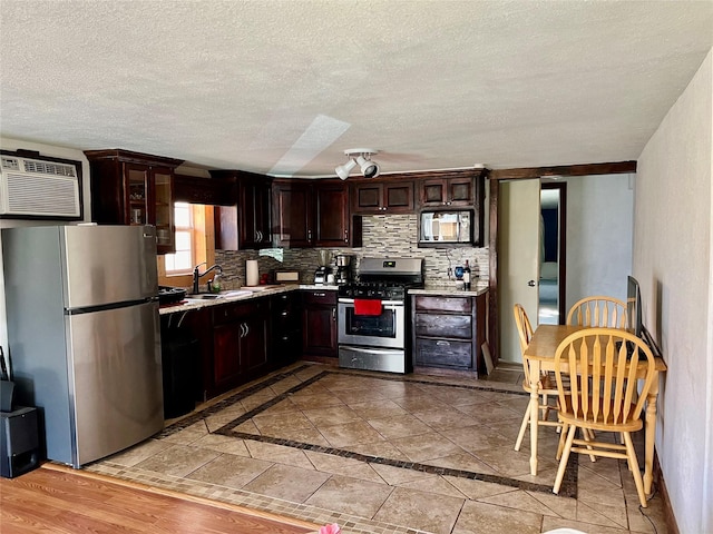 kitchen featuring tasteful backsplash, stainless steel appliances, dark brown cabinets, light countertops, and an AC wall unit