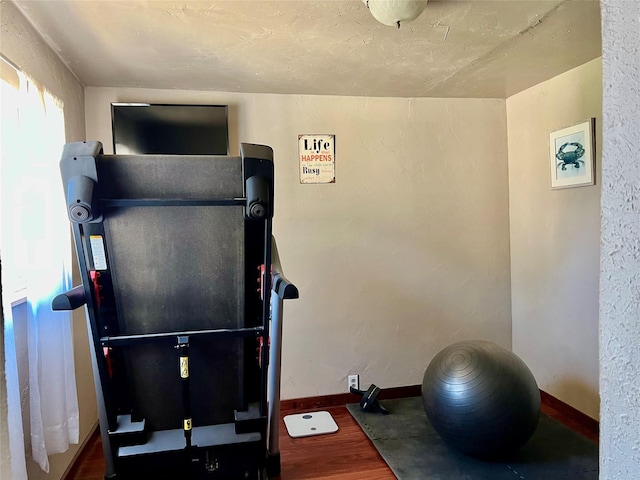 exercise room with baseboards and wood finished floors