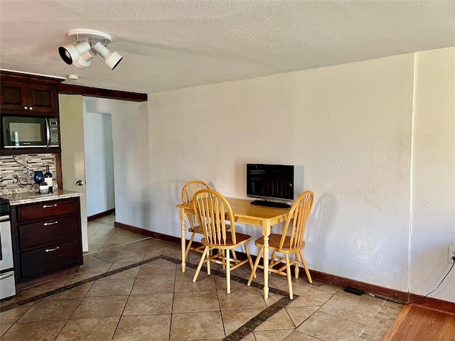 dining area with a textured ceiling, baseboards, and light tile patterned floors