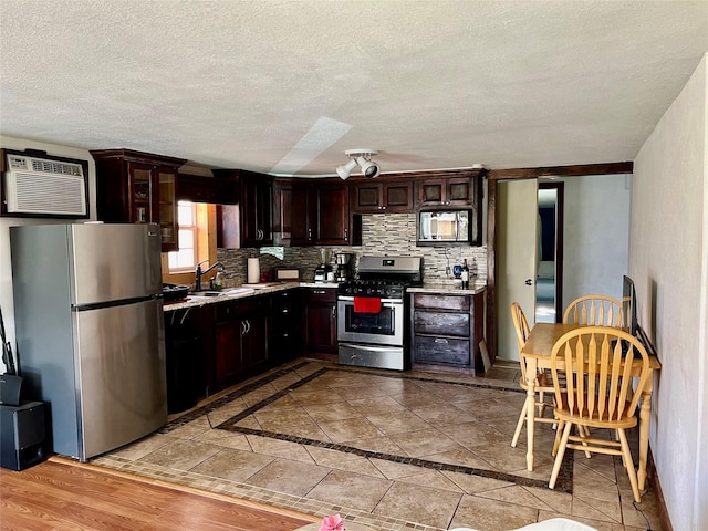 kitchen featuring dark brown cabinetry, tasteful backsplash, appliances with stainless steel finishes, light countertops, and an AC wall unit