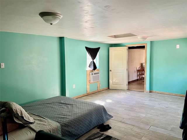 bedroom with cooling unit, baseboards, and wood finished floors