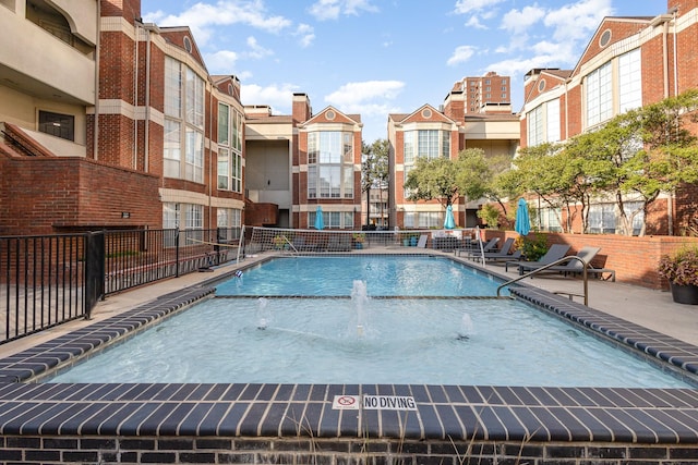 community pool with a patio area and fence