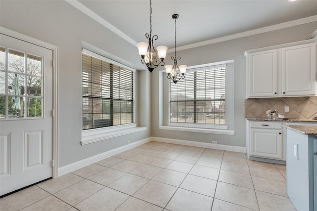 unfurnished dining area with a notable chandelier, crown molding, baseboards, and light tile patterned floors