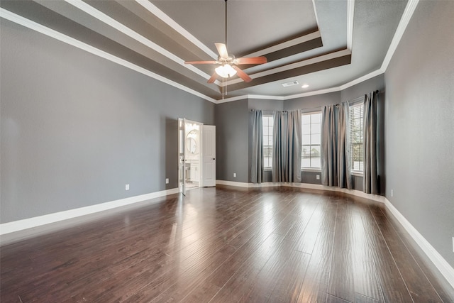 unfurnished room featuring a raised ceiling, visible vents, ornamental molding, wood finished floors, and baseboards