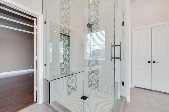 bathroom featuring tiled shower, baseboards, and wood finished floors