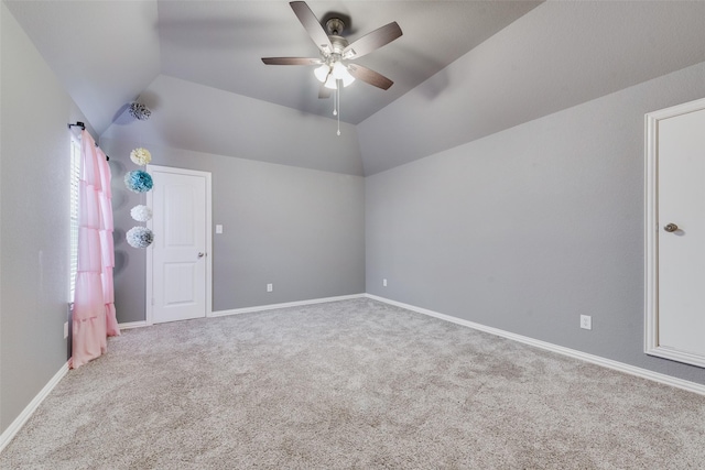 empty room with lofted ceiling, carpet flooring, a ceiling fan, and baseboards