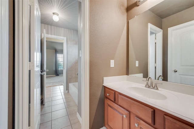 full bath featuring baseboards, a textured wall, tile patterned floors, a bathtub, and vanity