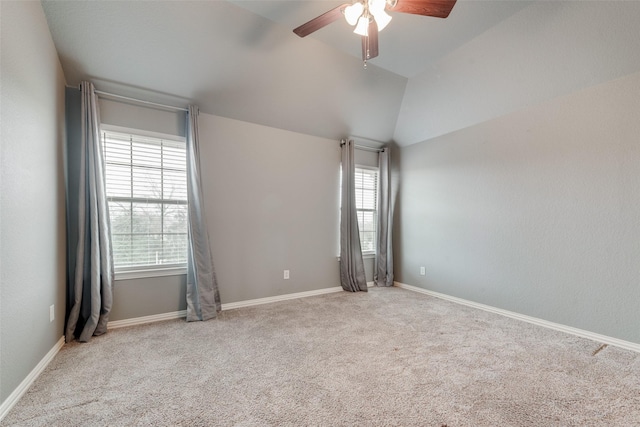 carpeted spare room with vaulted ceiling, baseboards, and ceiling fan