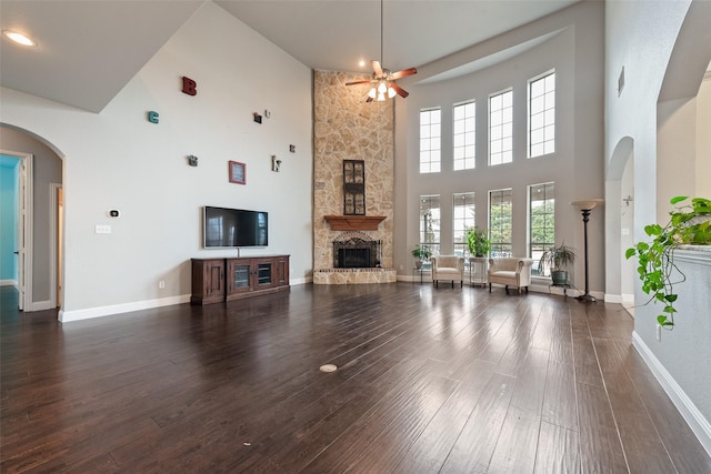 living room featuring arched walkways, a fireplace, wood finished floors, and baseboards