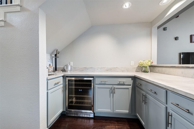 kitchen featuring lofted ceiling, beverage cooler, light countertops, gray cabinets, and dark wood finished floors