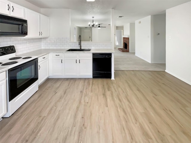 kitchen with light wood-style flooring, a sink, light countertops, decorative backsplash, and black appliances