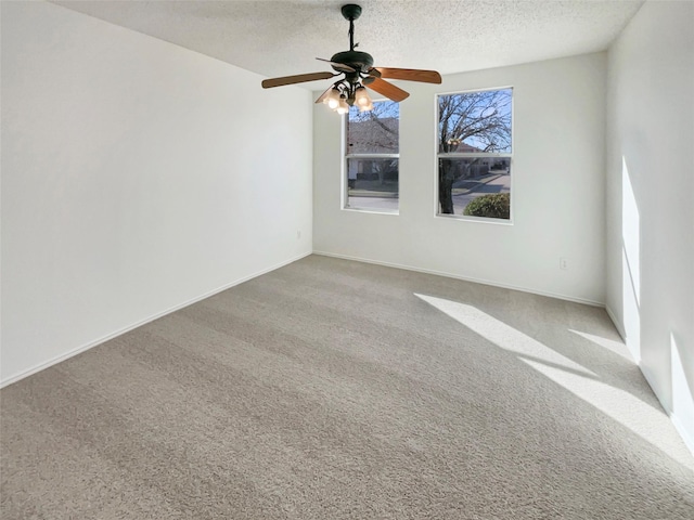 carpeted spare room featuring a ceiling fan, a textured ceiling, and baseboards