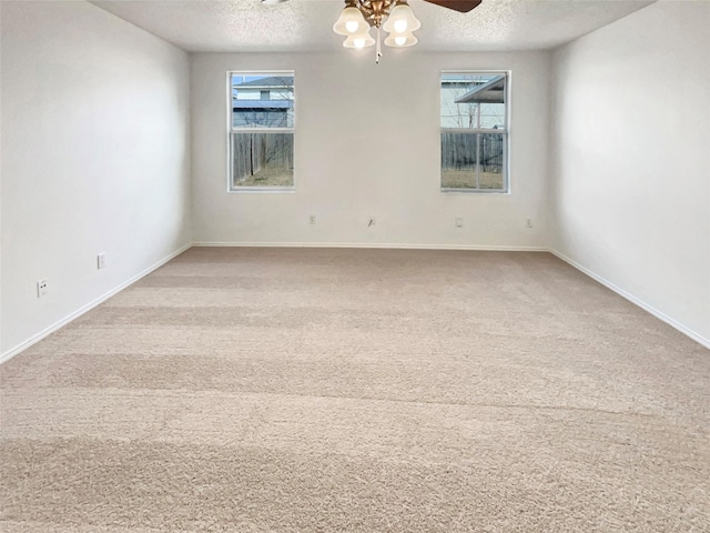 empty room featuring light carpet, a ceiling fan, baseboards, and a textured ceiling