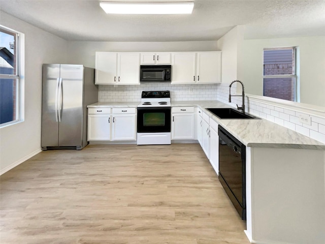 kitchen featuring a sink, white cabinetry, light countertops, decorative backsplash, and black appliances