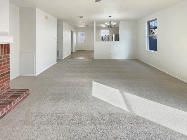 empty room featuring a notable chandelier, a fireplace, baseboards, and a healthy amount of sunlight