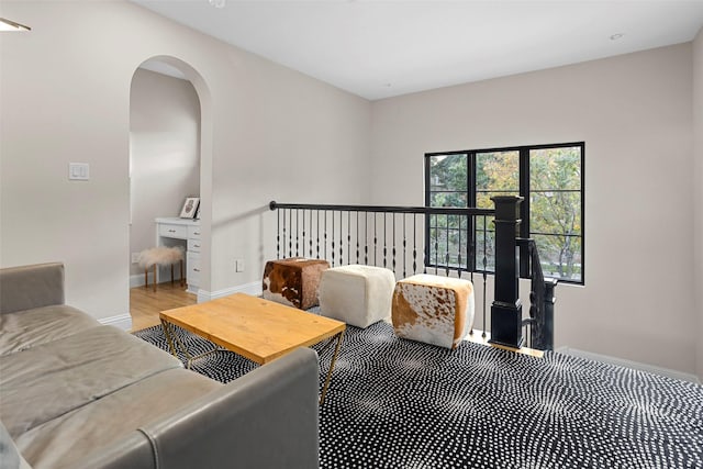 living area with baseboards, arched walkways, and wood finished floors