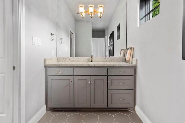 bathroom with tile patterned flooring, baseboards, a notable chandelier, and vanity