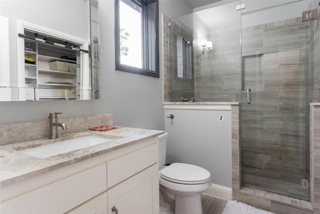 bathroom with vanity, a shower stall, and toilet