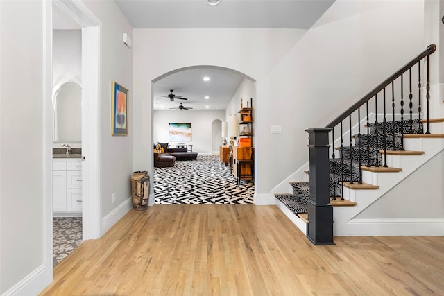 foyer entrance with arched walkways, ceiling fan, and wood finished floors