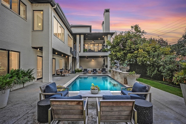 pool at dusk featuring an outdoor pool, stairway, outdoor lounge area, and a patio