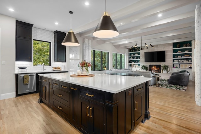 kitchen with a fireplace, a wealth of natural light, light countertops, light wood-style floors, and dishwasher