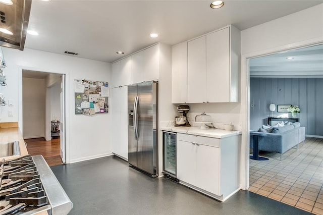 kitchen featuring wine cooler, visible vents, white cabinets, light countertops, and stainless steel fridge