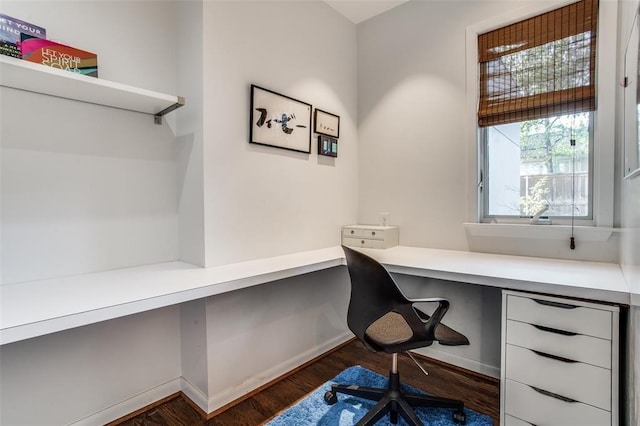 office area featuring built in desk, baseboards, and wood finished floors