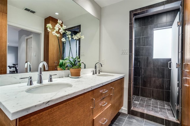 bathroom featuring double vanity, a stall shower, visible vents, and a sink