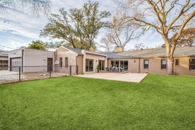 back of house featuring a patio, brick siding, fence, a yard, and a chimney