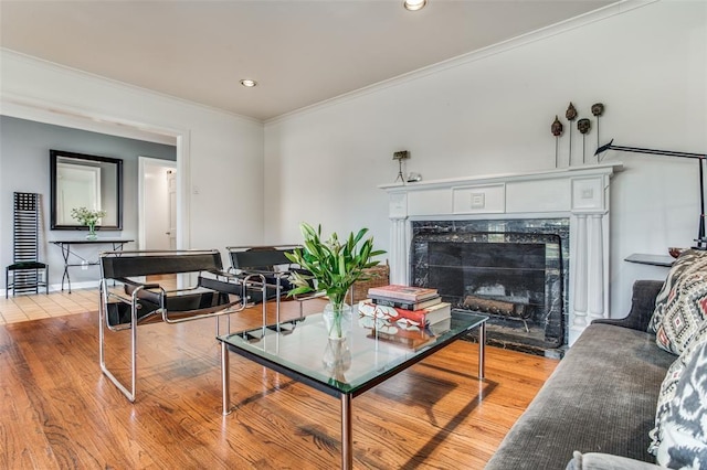 living room featuring ornamental molding, recessed lighting, a high end fireplace, and light wood-style floors