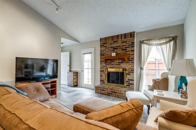 tiled living room featuring a brick fireplace, a textured ceiling, vaulted ceiling, and a wealth of natural light