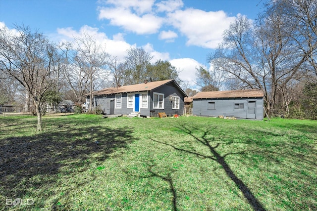 view of front of house with entry steps, a front yard, and an outdoor structure