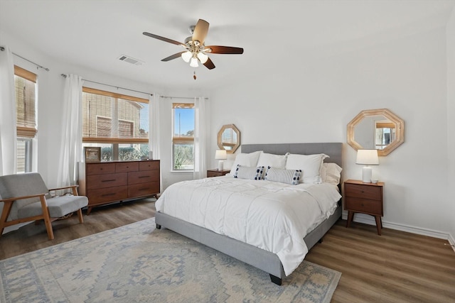 bedroom featuring a ceiling fan, baseboards, visible vents, and wood finished floors