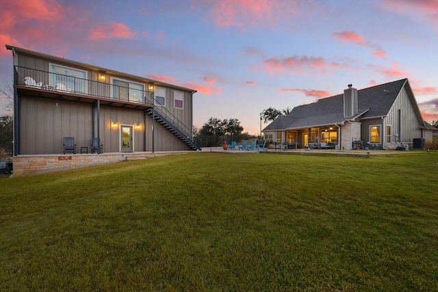 rear view of property featuring board and batten siding, central air condition unit, stairs, and a lawn