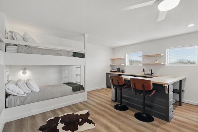 bedroom with light wood-type flooring, a sink, and baseboards