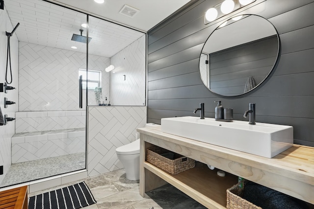 bathroom featuring visible vents, tiled shower, toilet, marble finish floor, and a sink