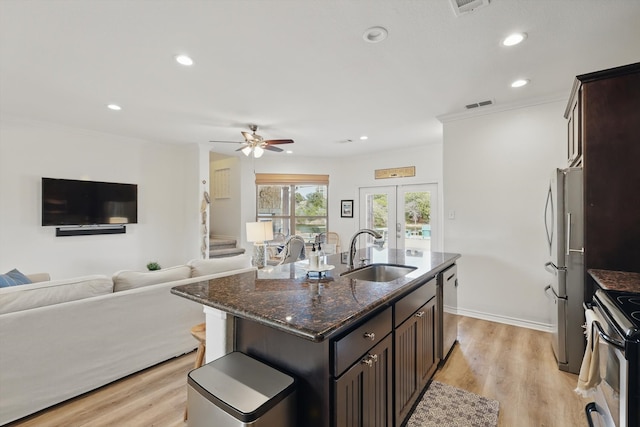 kitchen featuring visible vents, appliances with stainless steel finishes, open floor plan, a sink, and light wood-type flooring