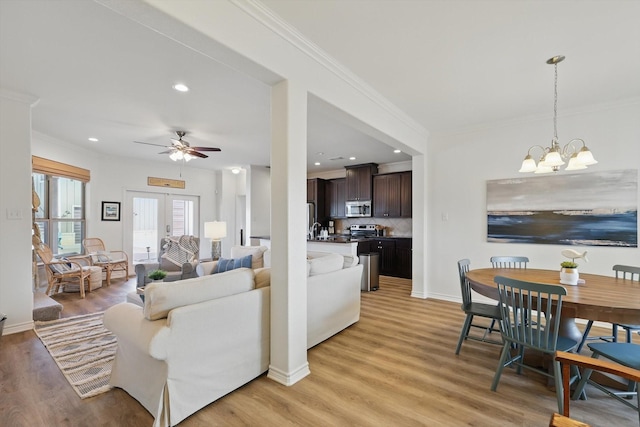 living room featuring recessed lighting, ornamental molding, light wood-type flooring, baseboards, and ceiling fan with notable chandelier