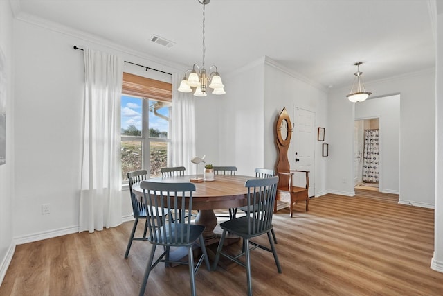 dining space featuring a notable chandelier, wood finished floors, visible vents, baseboards, and crown molding