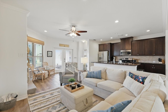 living area with ornamental molding, light wood-type flooring, french doors, and recessed lighting