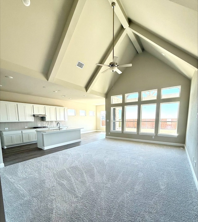 kitchen with visible vents, white cabinets, open floor plan, beamed ceiling, and high vaulted ceiling