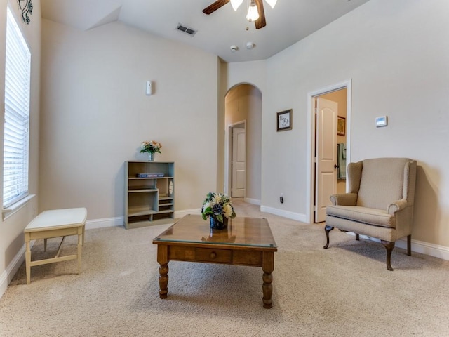 living area featuring arched walkways, carpet flooring, visible vents, baseboards, and a ceiling fan