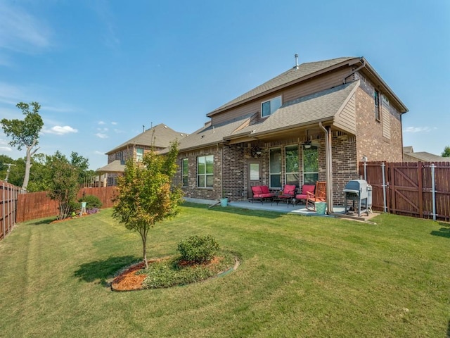 back of house featuring brick siding, a lawn, a patio area, and a fenced backyard