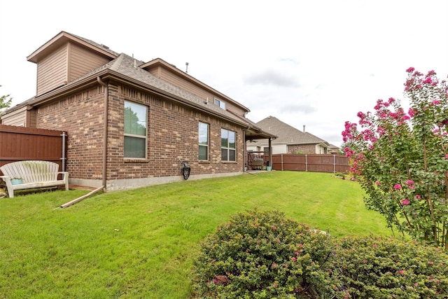 rear view of property featuring brick siding, a lawn, and fence