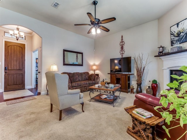 carpeted living room with arched walkways, visible vents, baseboards, and ceiling fan with notable chandelier