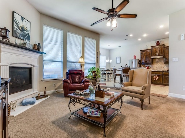 living area with a ceiling fan, a glass covered fireplace, light colored carpet, and recessed lighting